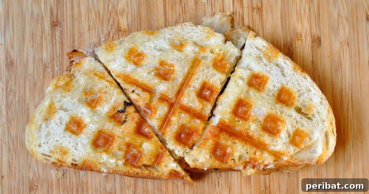 A classic ham and turkey panini with melted cheese, perfectly pressed and grilled in a waffle iron, showing crisp edges.