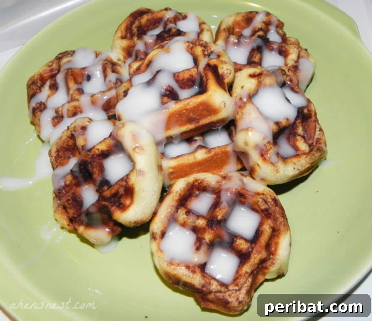 Warm and gooey cinnamon rolls cooked in a waffle iron, drizzled with sweet icing and showcasing unique waffle patterns.