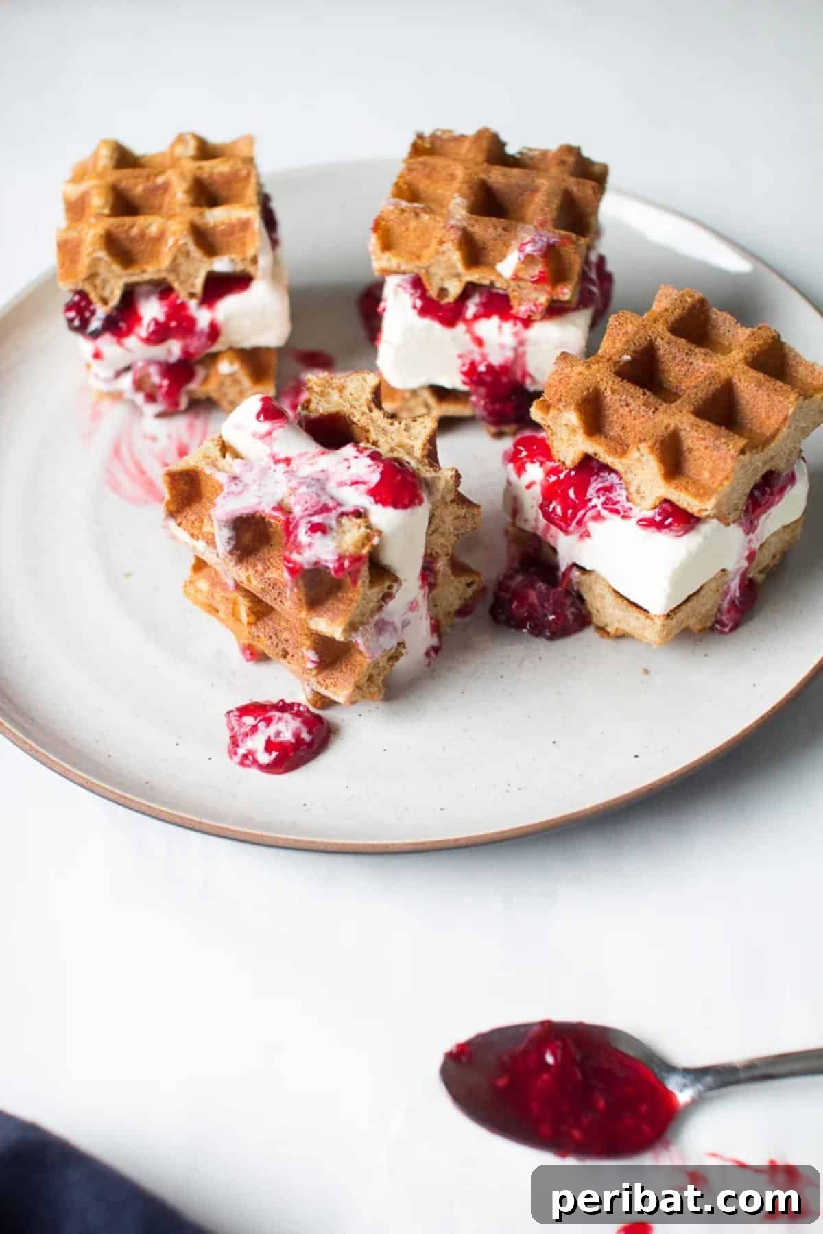 Delightful mini ice cream waffle sandwiches with fresh berries, showcasing creamy ice cream nestled between crispy, textured waffle cookies.