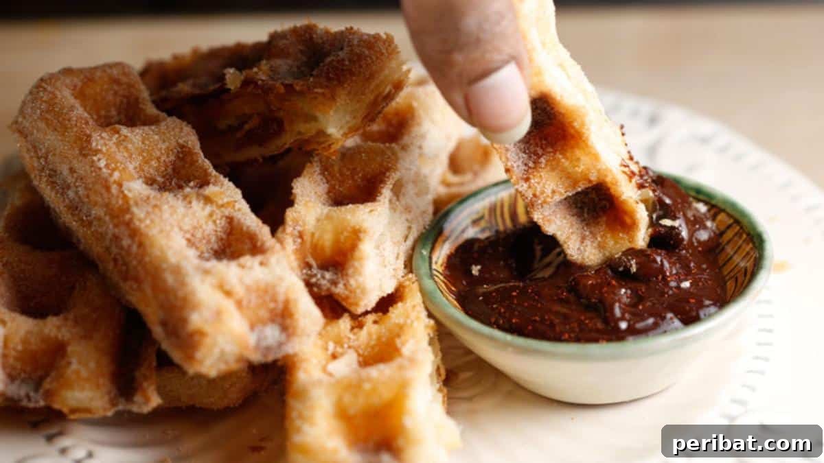 Golden-brown churros, cooked in a waffle iron, forming unique shapes with distinct waffle patterns, ready for dipping.