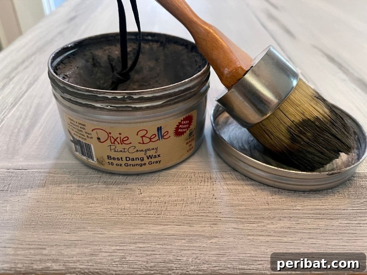 Applying grey wax to a distressed desk, enhancing the texture and color variations.