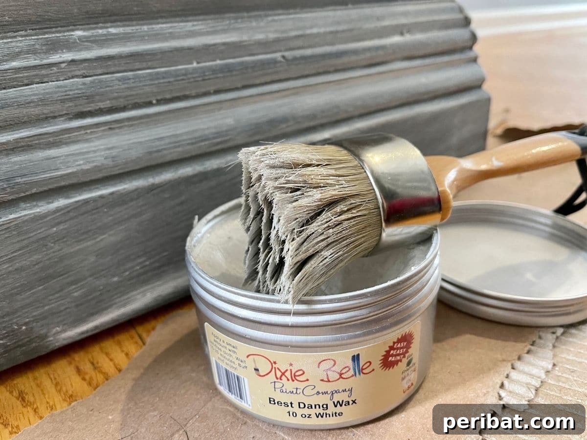 Applying white wax to the trim of a distressed desk to highlight details and create contrast.