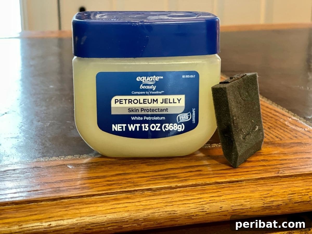 Petroleum jelly being applied to strategic areas of a desk to create a distressed effect.