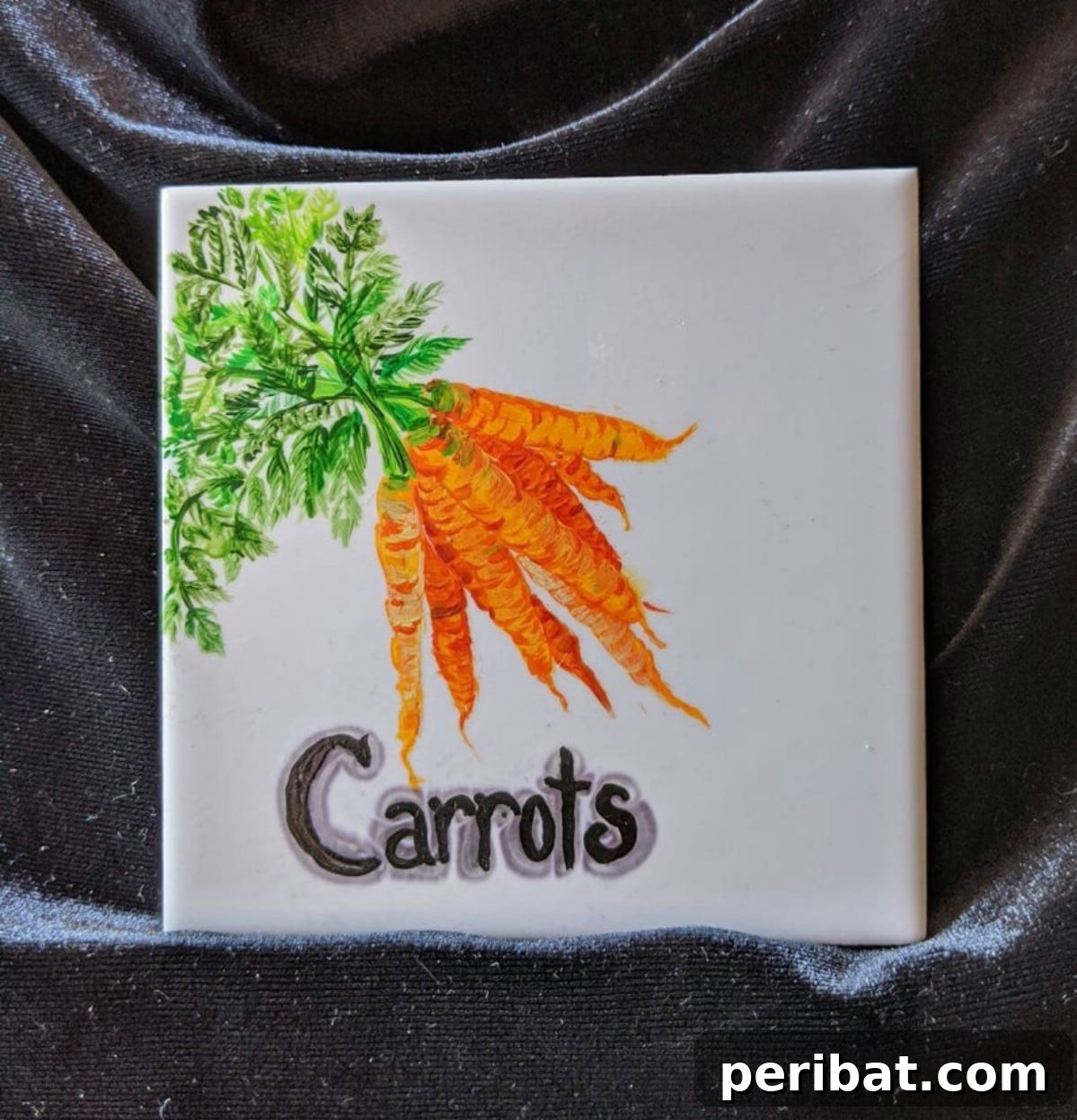 White tile with carrots painted and word carrots painted on top
