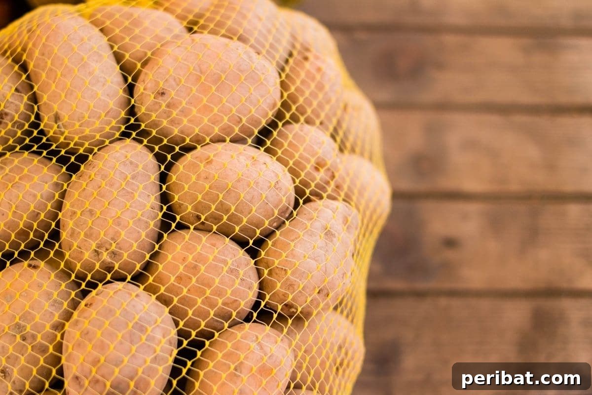 Potatoes stored in a breathable netted bag on a wooden table, emphasizing good airflow to prevent moisture buildup and spoilage.