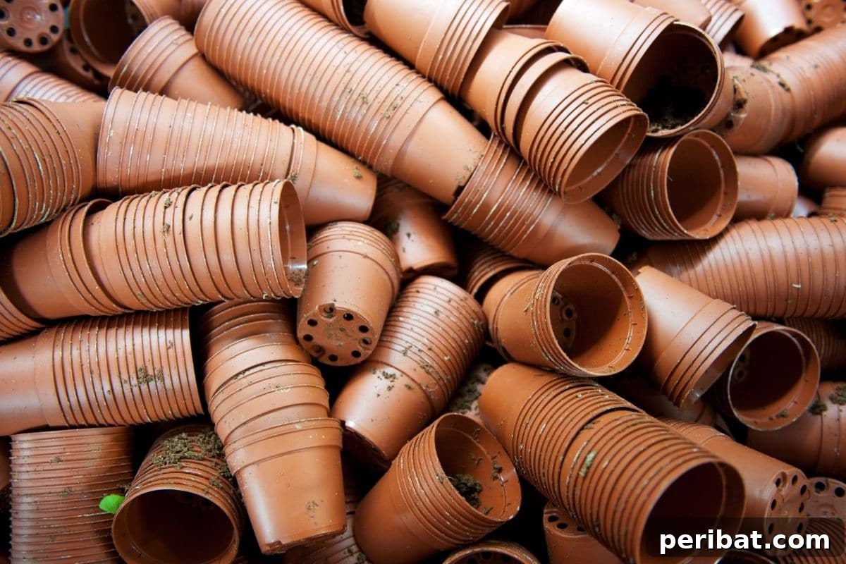 Stock of dirty, used nursery pots with multiple drainage holes, ready for reuse