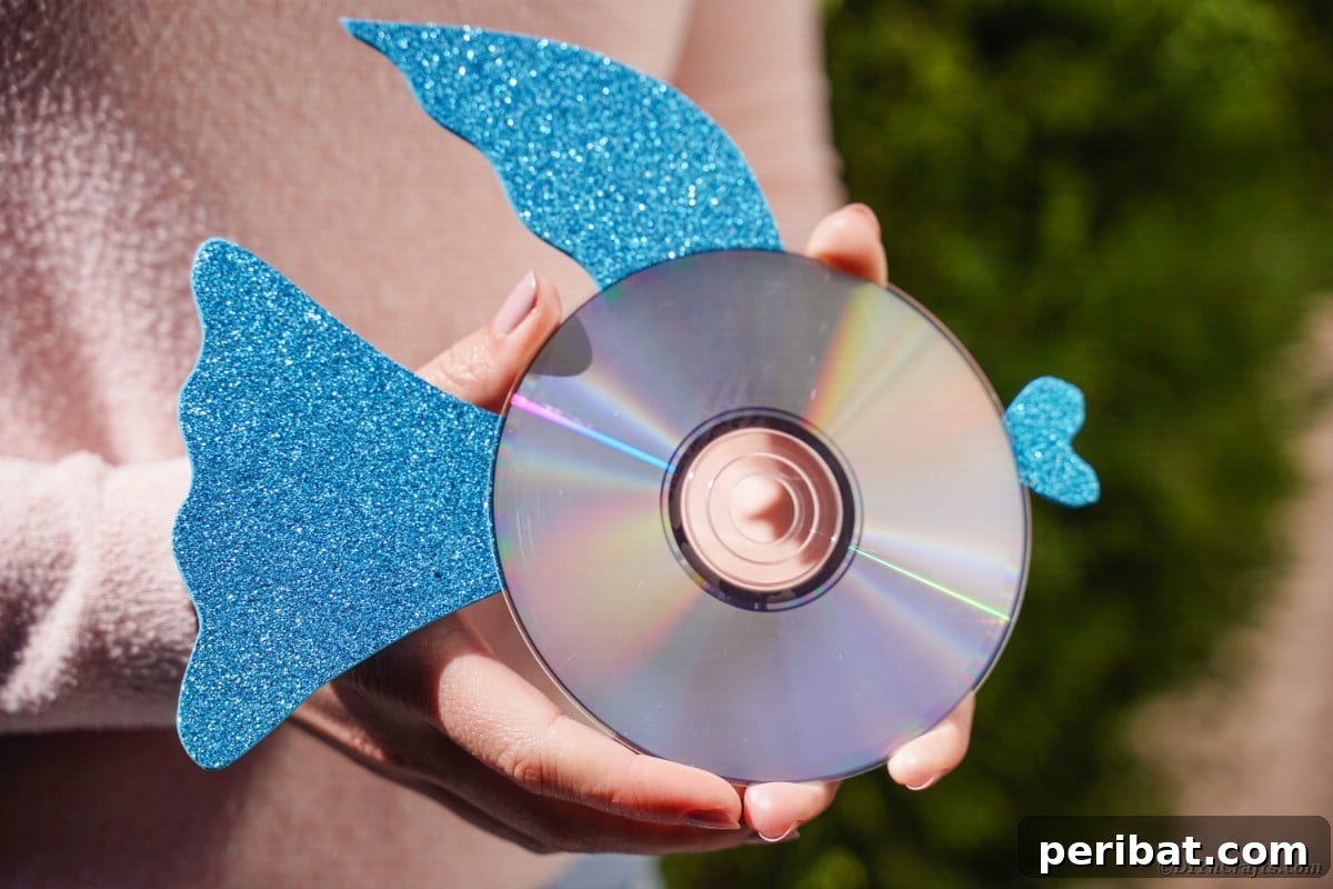 Crafting Whimsical Fish and Bird Decor from Old CDs 4 Woman holding blue CD fish