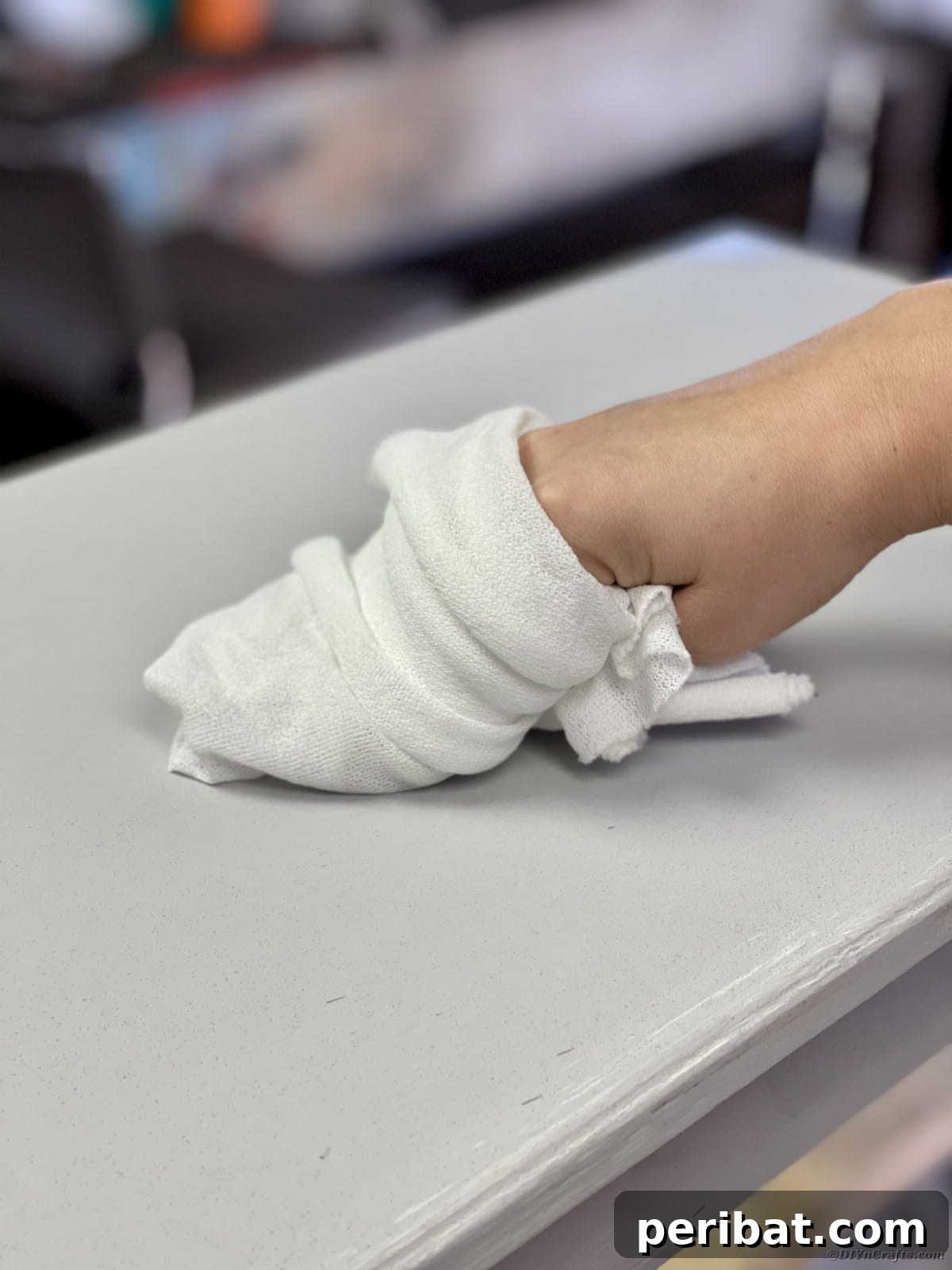 Wiping dust off a painted bench with a lint-free cloth after light sanding