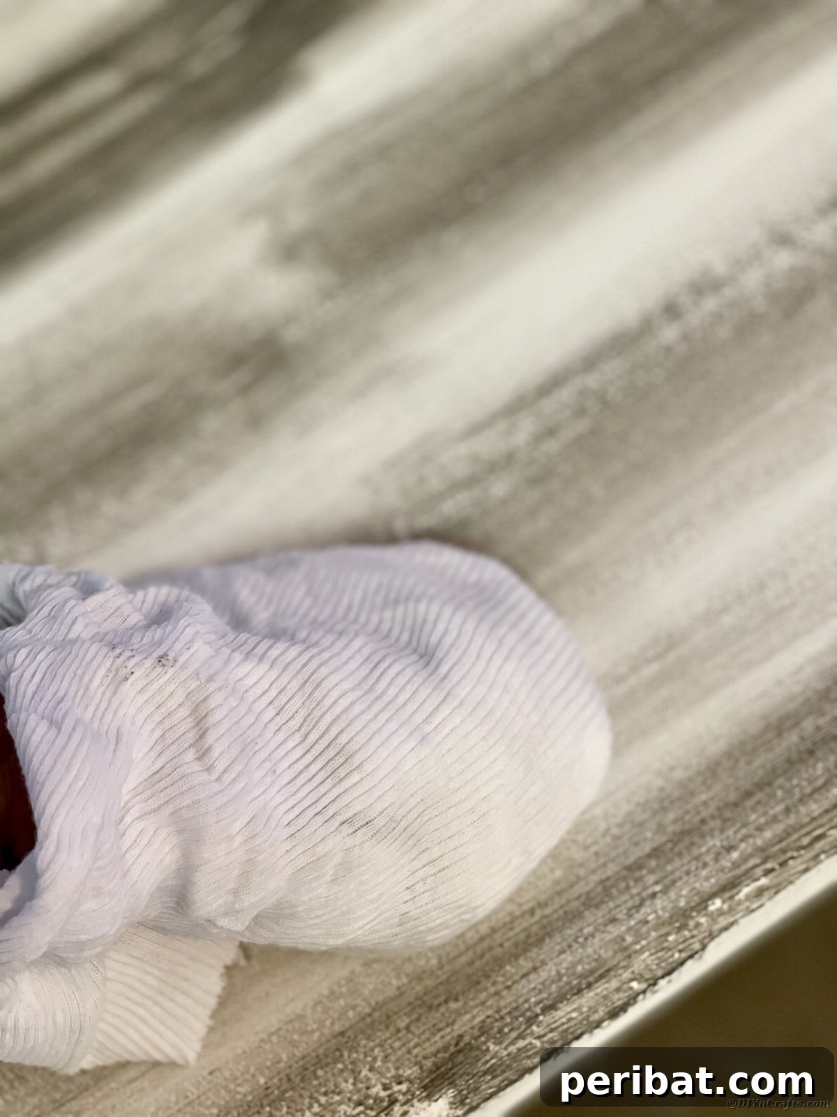 Vigorously wiping and buffing wax into a distressed wooden bench with a lint-free cloth