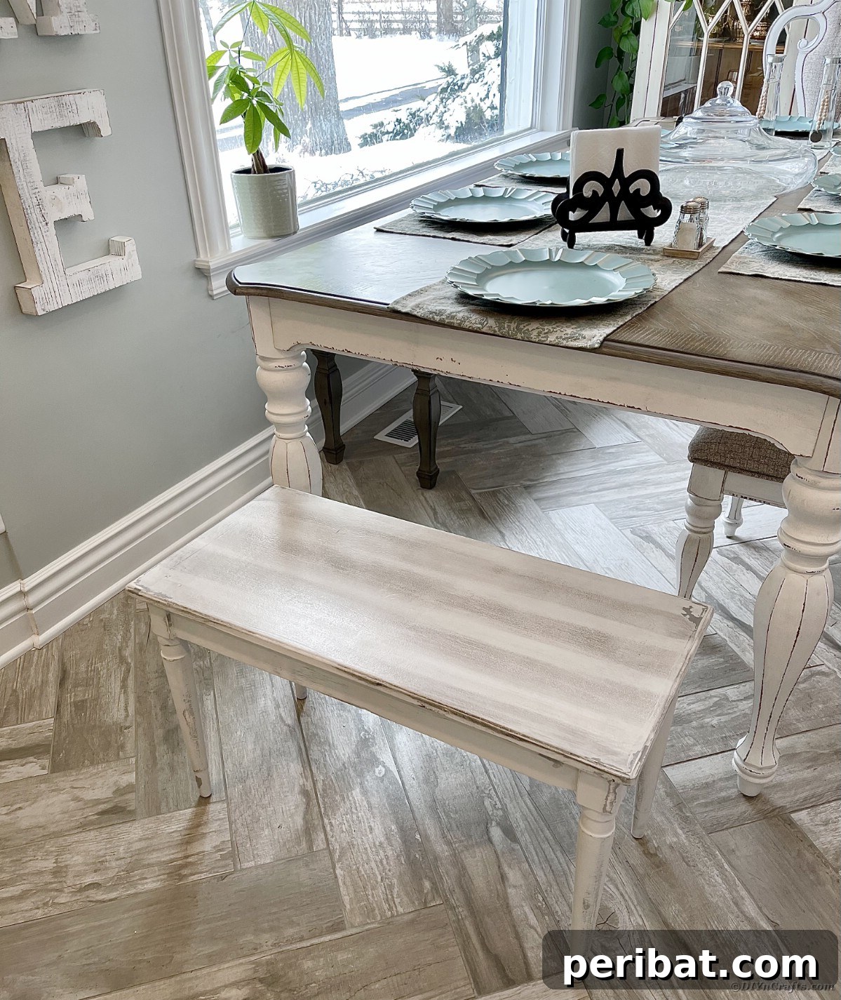 Close-up of a distressed dining table and bench, showcasing textured paint and worn edges