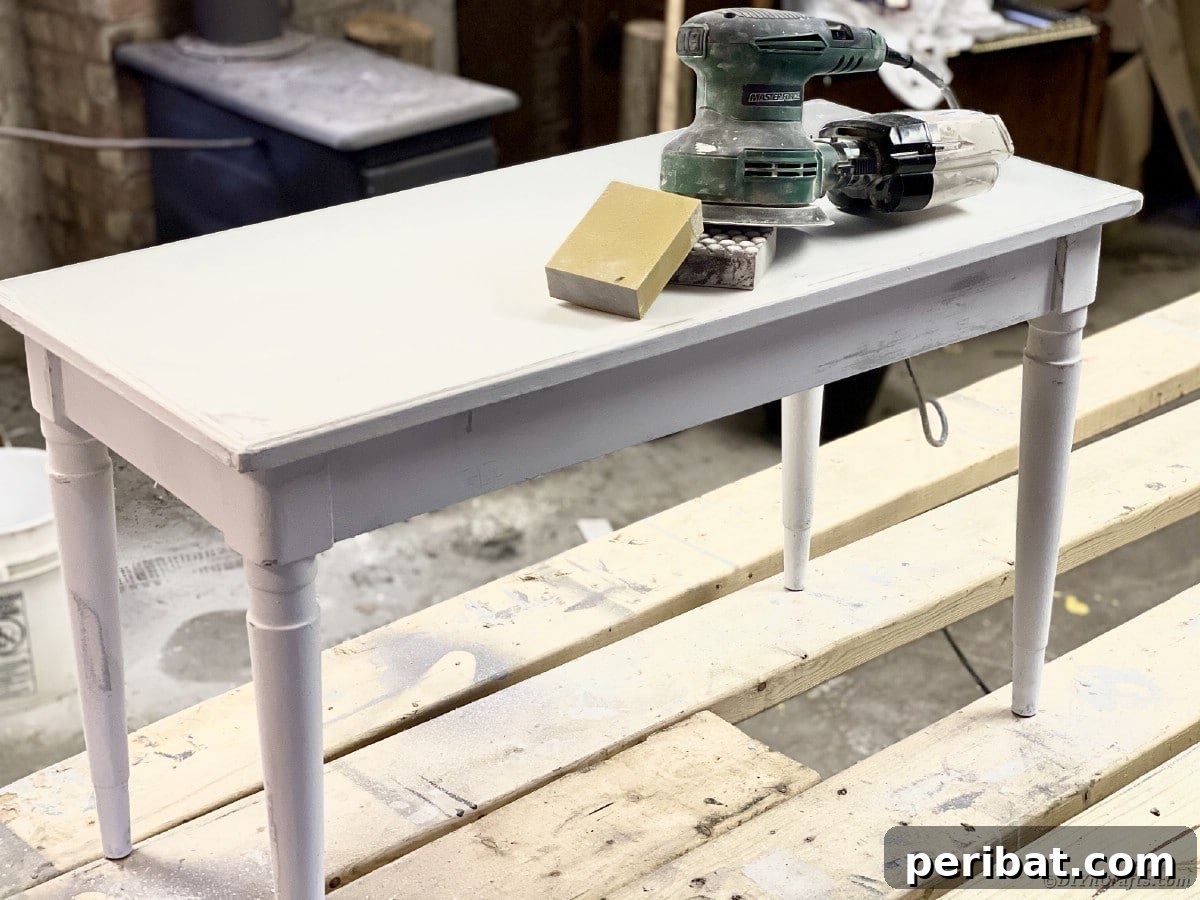 Sanding a wooden bench with an orbital sander to prepare for distressing