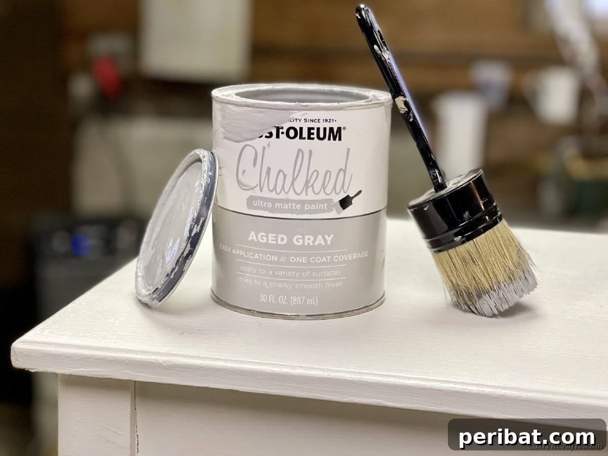 Can of Rust-Oleum Aged Gray Chalked Paint and a natural bristle brush on a distressed bench