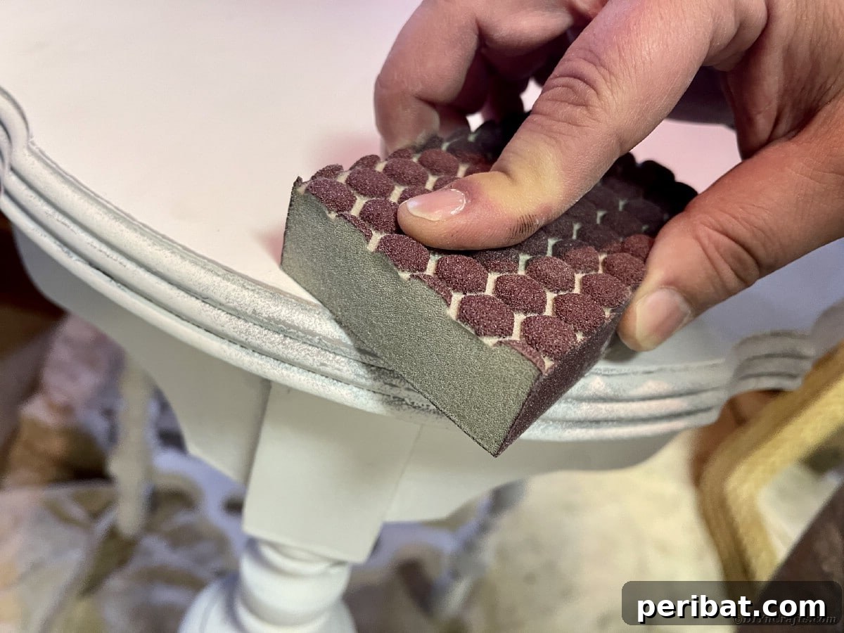 Chippy Charm Side Table Transformation 13 Hand holding sanding block on corner of white side table