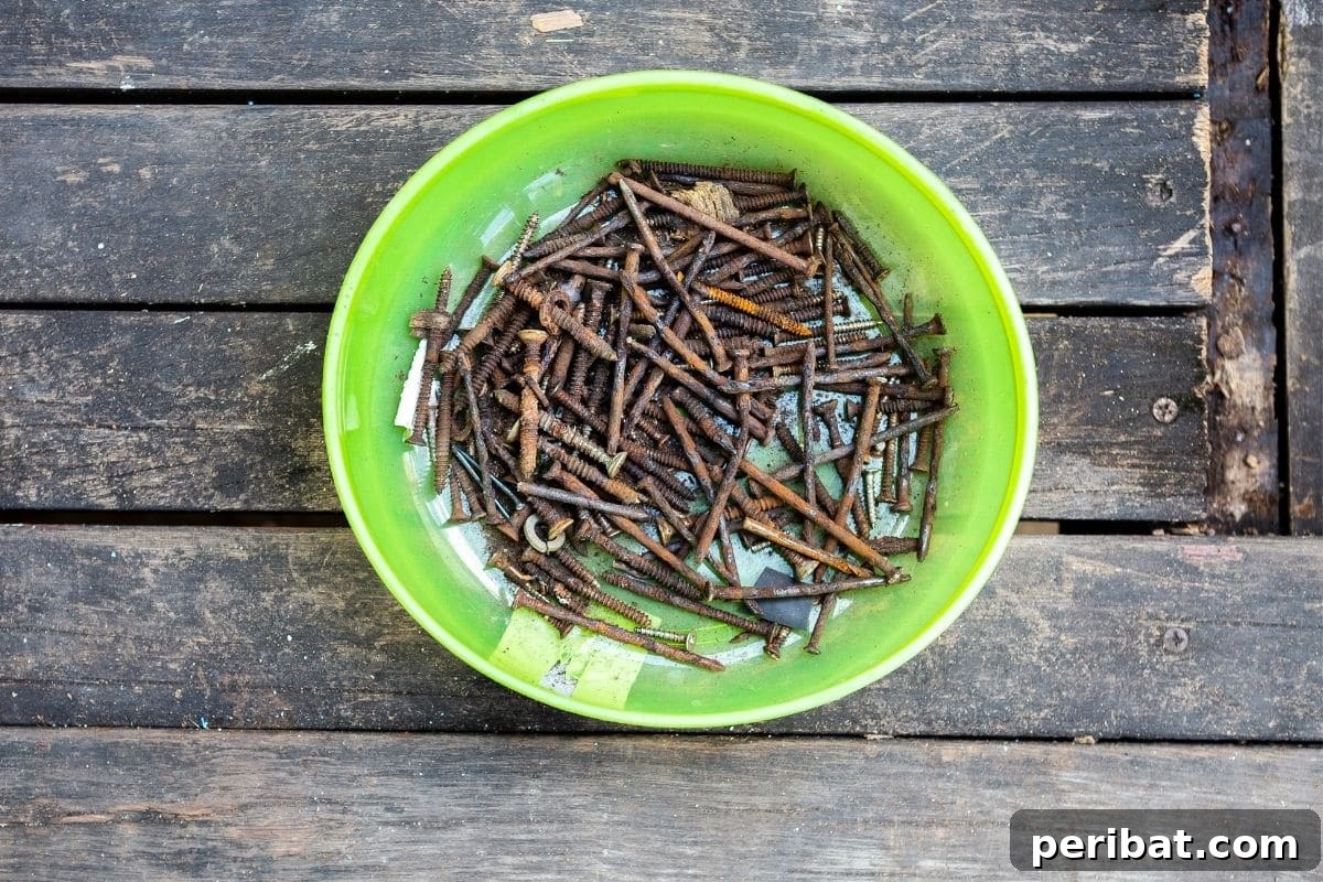 The Rusty Nail Trick Your Plants Are Craving 5 rusty nails in a green bowl placed in the wooden table