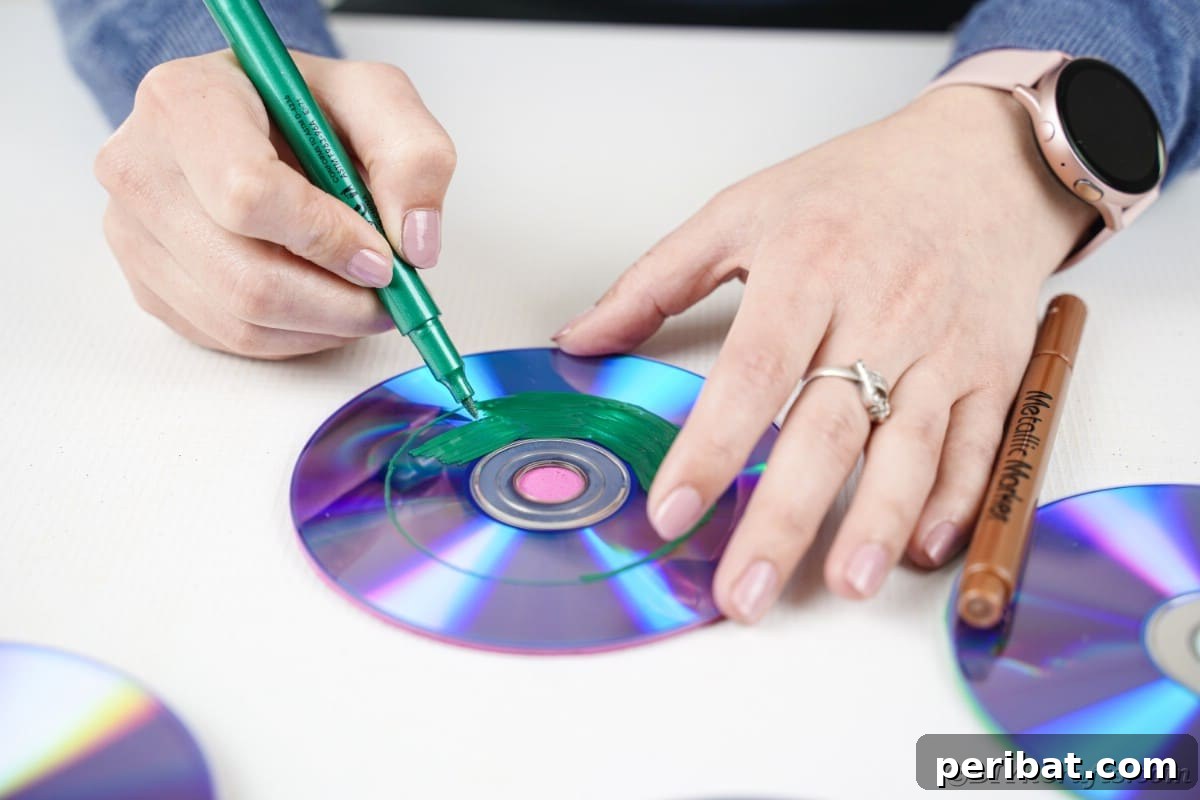 Sparkling Repurposed Garden Melody 11 A close-up of a hand painting a CD with a vibrant green design, adding intricate details.
