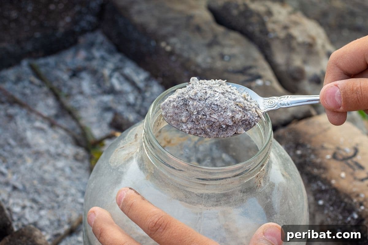 Boost Your Garden: 5 Wood Ash Uses and Storage Guide 9 Putting wood ash into a glass jar for storage, demonstrating careful handling