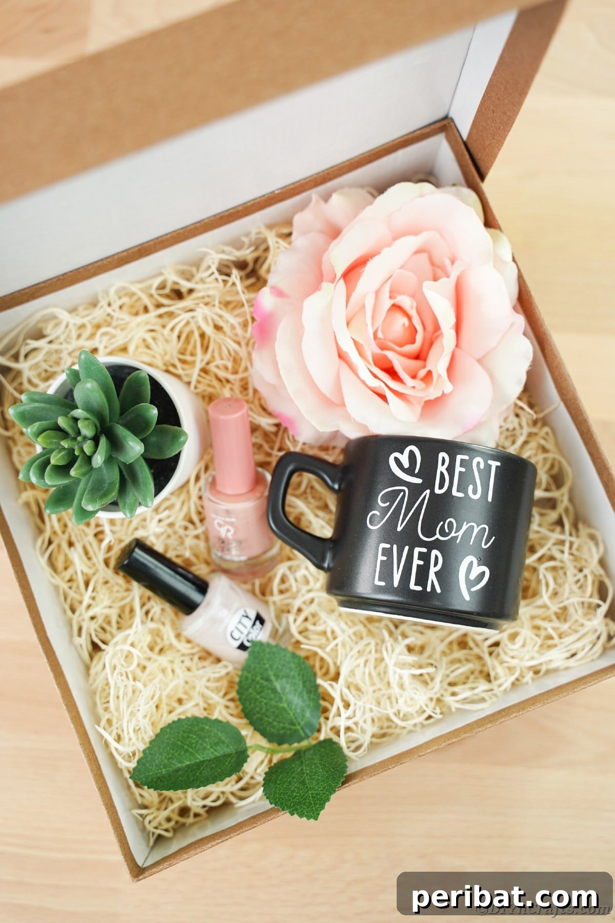 A large gift box containing faux hay, flowers, nail polish, and a black Mother's Day mug, highlighting a beautiful gift presentation.