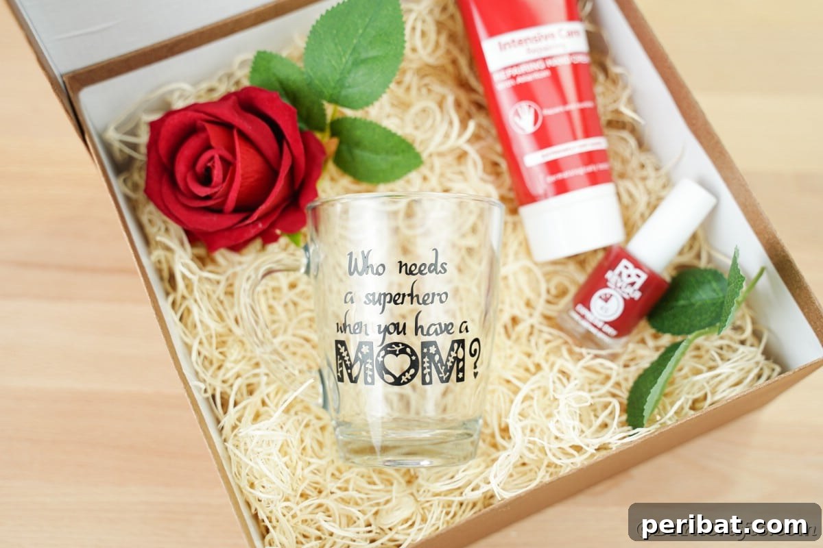 An elegantly arranged gift box containing a clear glass mug, delicate fresh flowers, and other thoughtful items, perfect for Mother's Day.