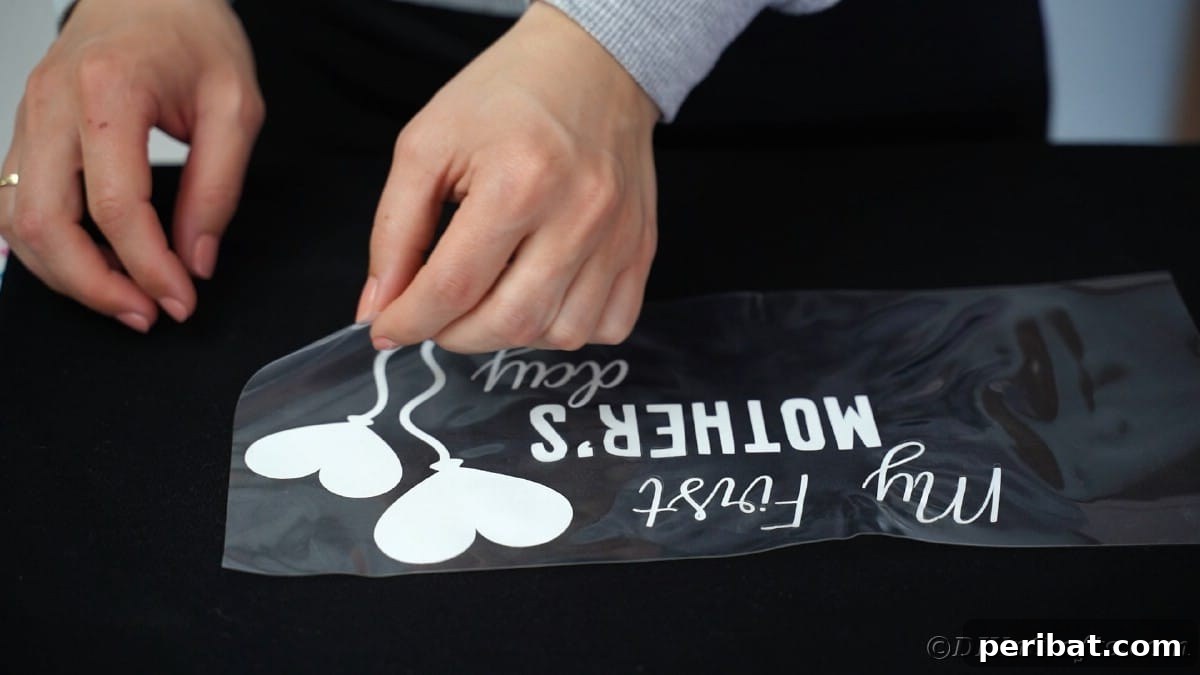 Peeling carrier sheet off the top of a black custom t-shirt