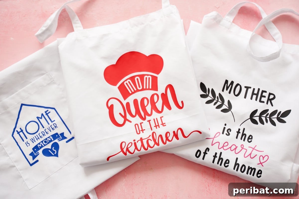 Three beautifully customized aprons featuring various Cricut vinyl designs, neatly arranged on a pink table, ready for gifting this Mother's Day.