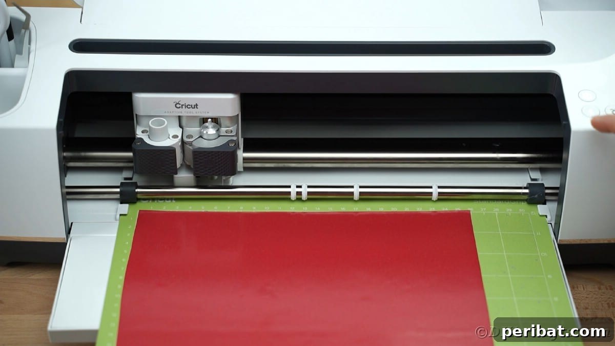 A Cricut cutting machine is shown with a green mat loaded into it, ready to begin the cutting process for a vinyl project.