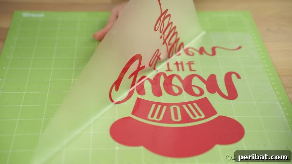 Hands carefully peel a sheet of heat transfer vinyl, attached to transfer tape, off of a green Cricut mat.