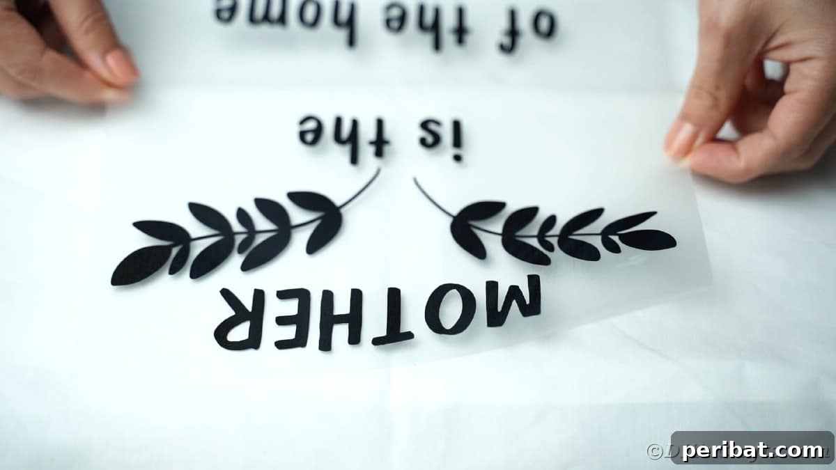 A hand carefully places the first layer of a multi-color vinyl design onto a white apron, ensuring precise alignment.