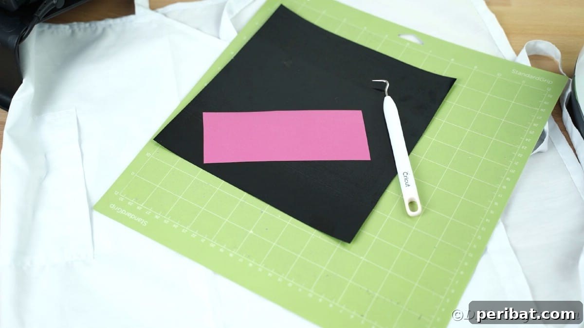 Black and pink heat transfer vinyl sheets are carefully arranged on a green Cricut cutting mat, prepared for a multi-color design project.