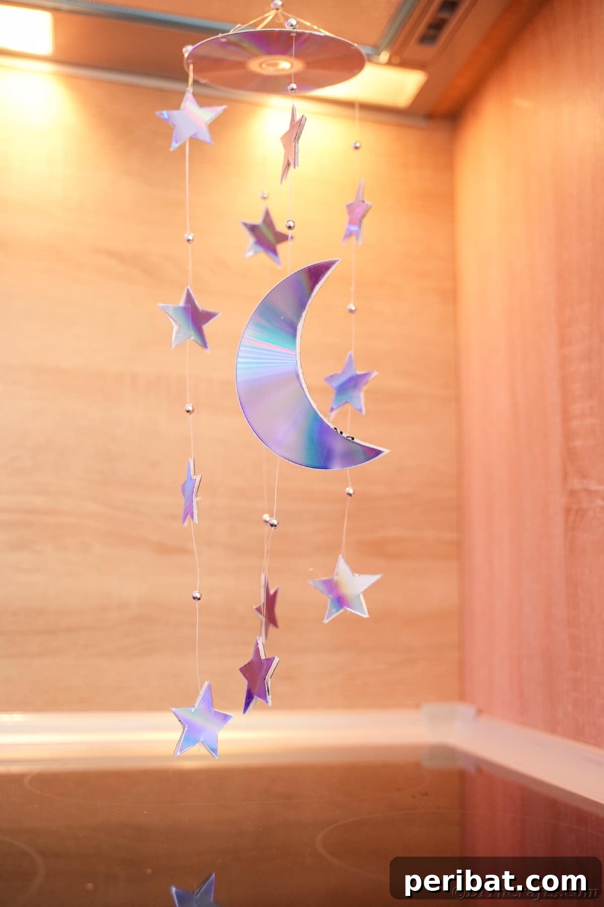 Celestial Sparkle DIY Upcycled CD Moon and Stars Baby Mobile 25 Mobile hung from ceiling in front of wooden walls
