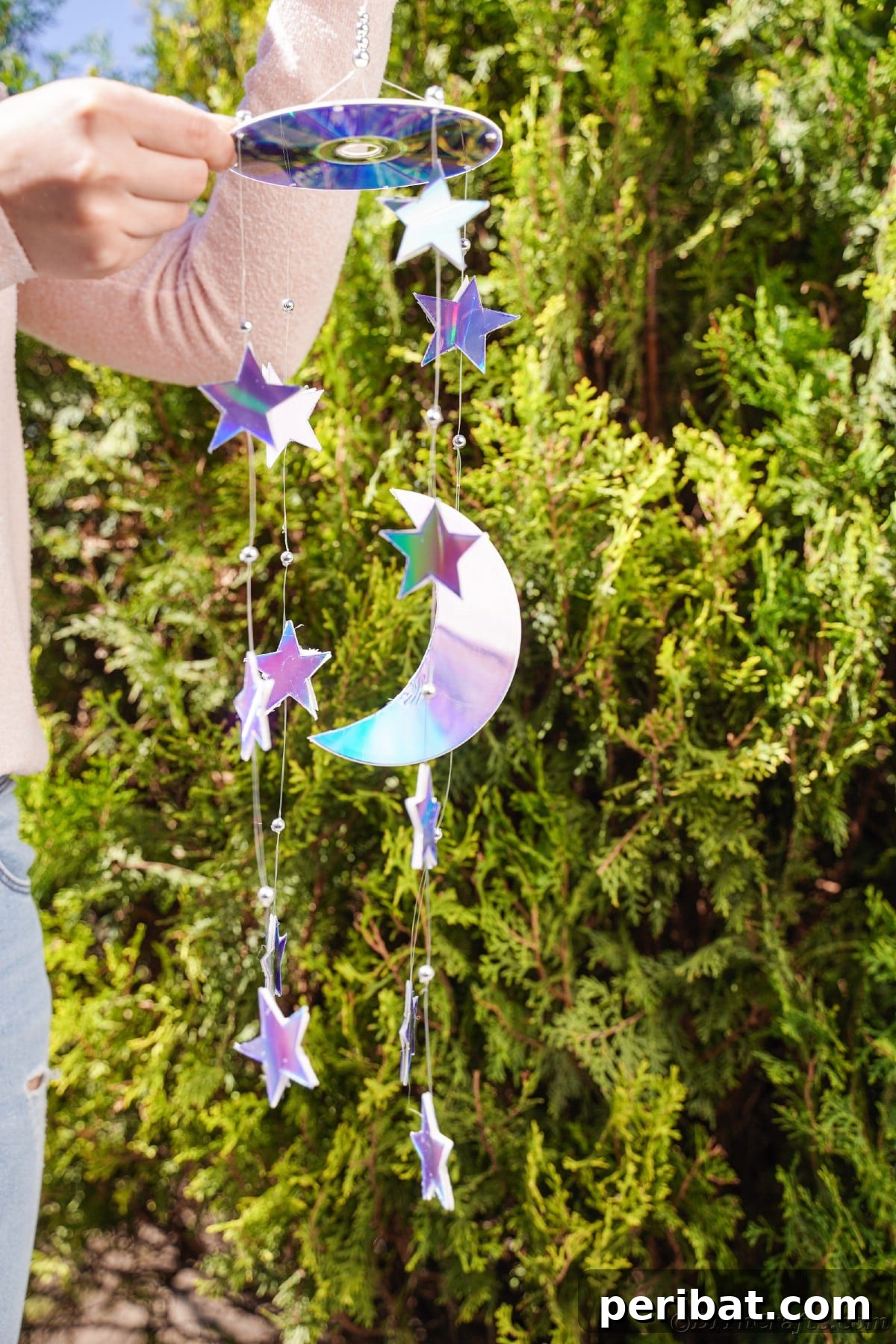Celestial Sparkle DIY Upcycled CD Moon and Stars Baby Mobile 26 Woman holding mobile in front of shrub