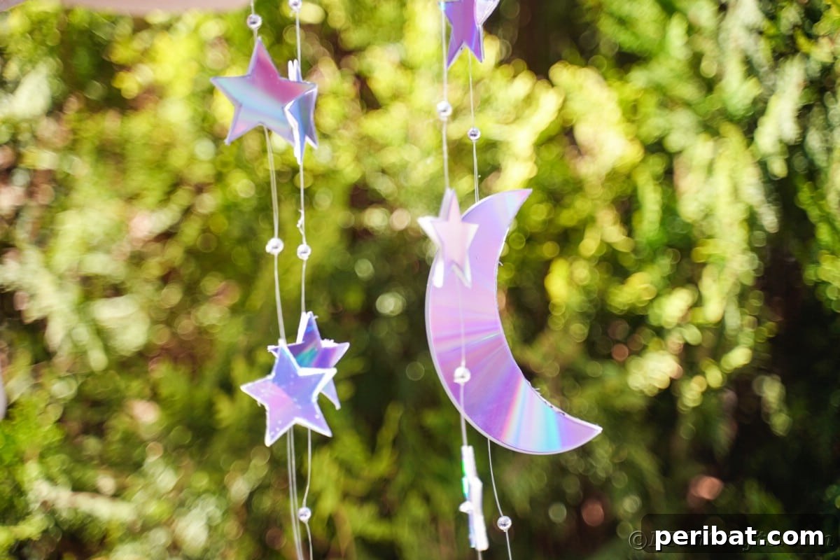 Celestial Sparkle DIY Upcycled CD Moon and Stars Baby Mobile 6 CD cut into star and moon strung on fishing line in front of shrub