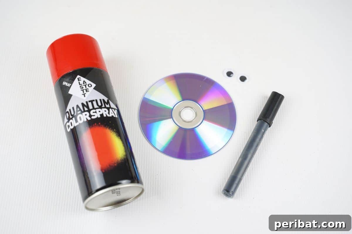 A can of red spray paint, an old CD, and a black permanent marker laid out on a table, ready for crafting.
