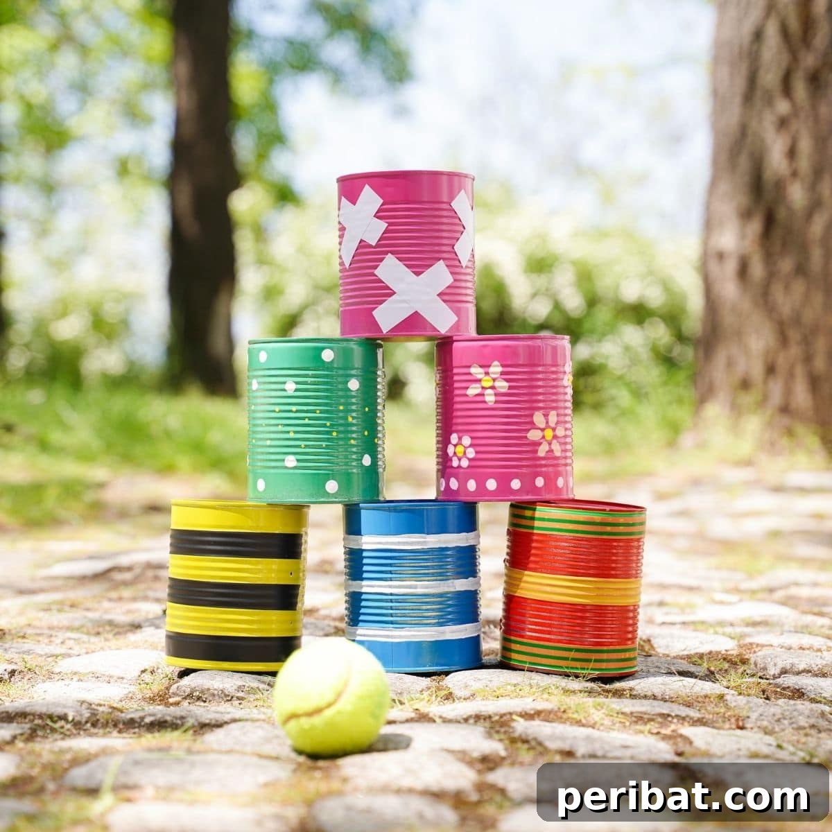 Six painted tin cans stacked together on stone