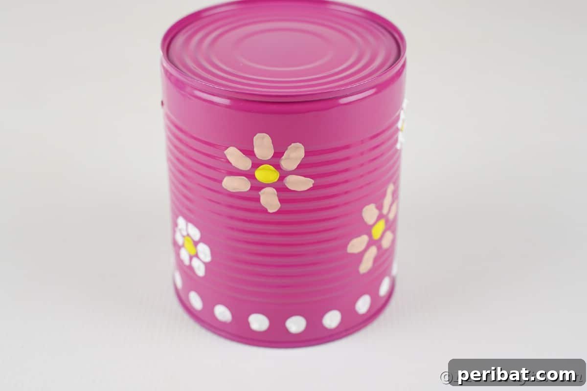Pink can with white dots and pink flowers painted on the outside
