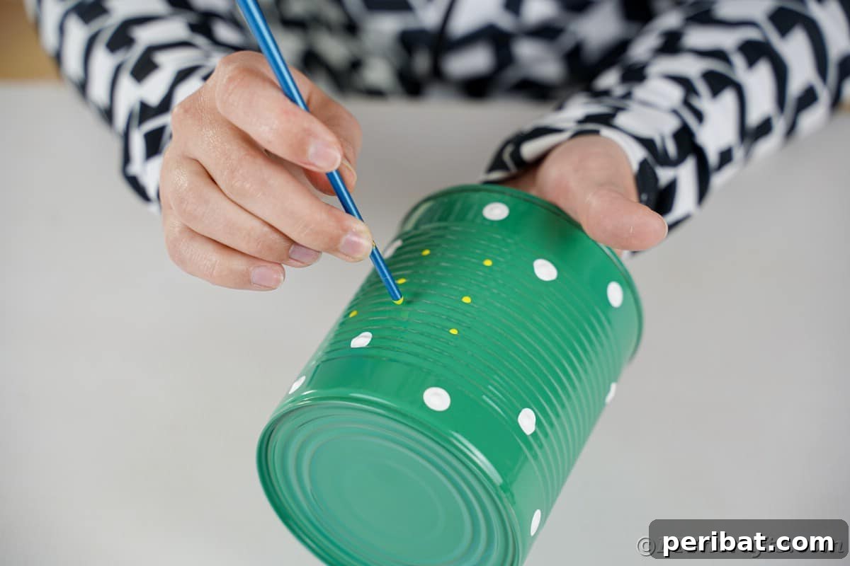Painting yellow dots on green tin can