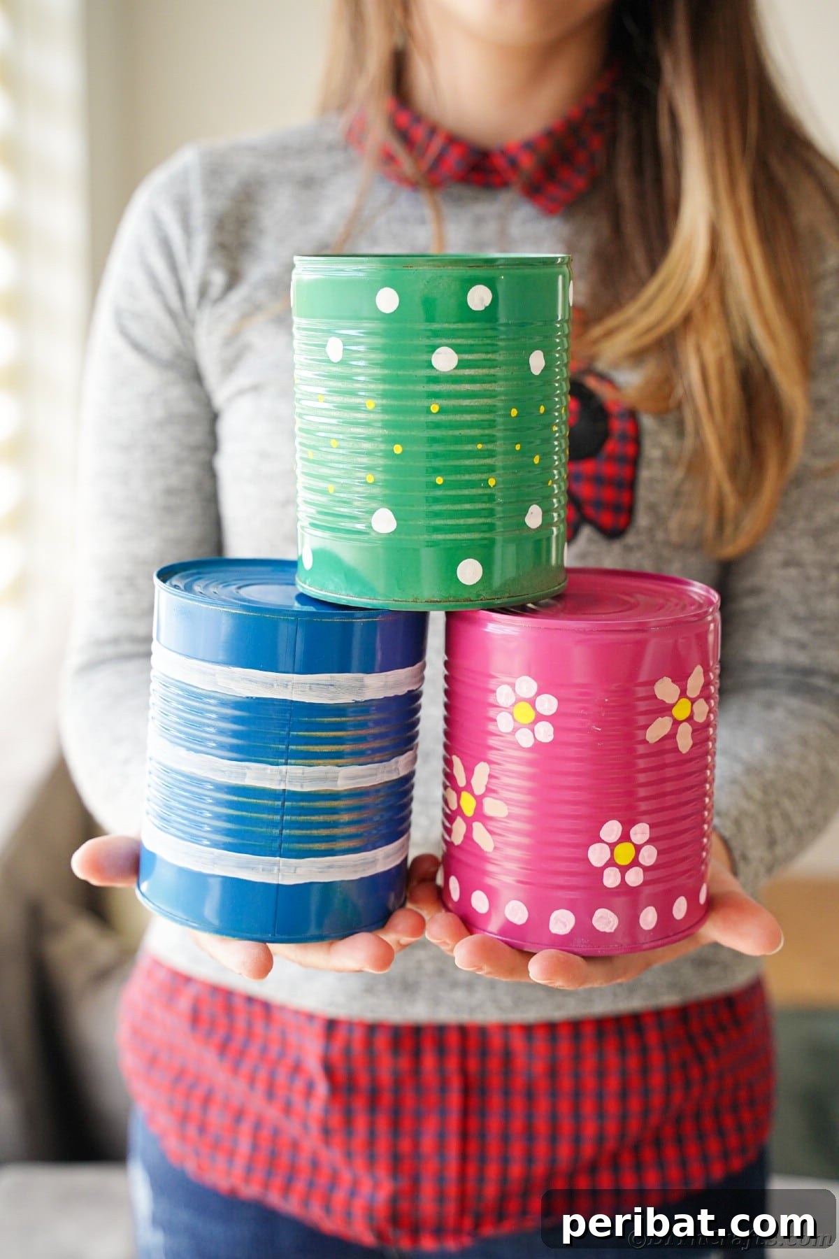 Woman holding pink green and blue tin cans 