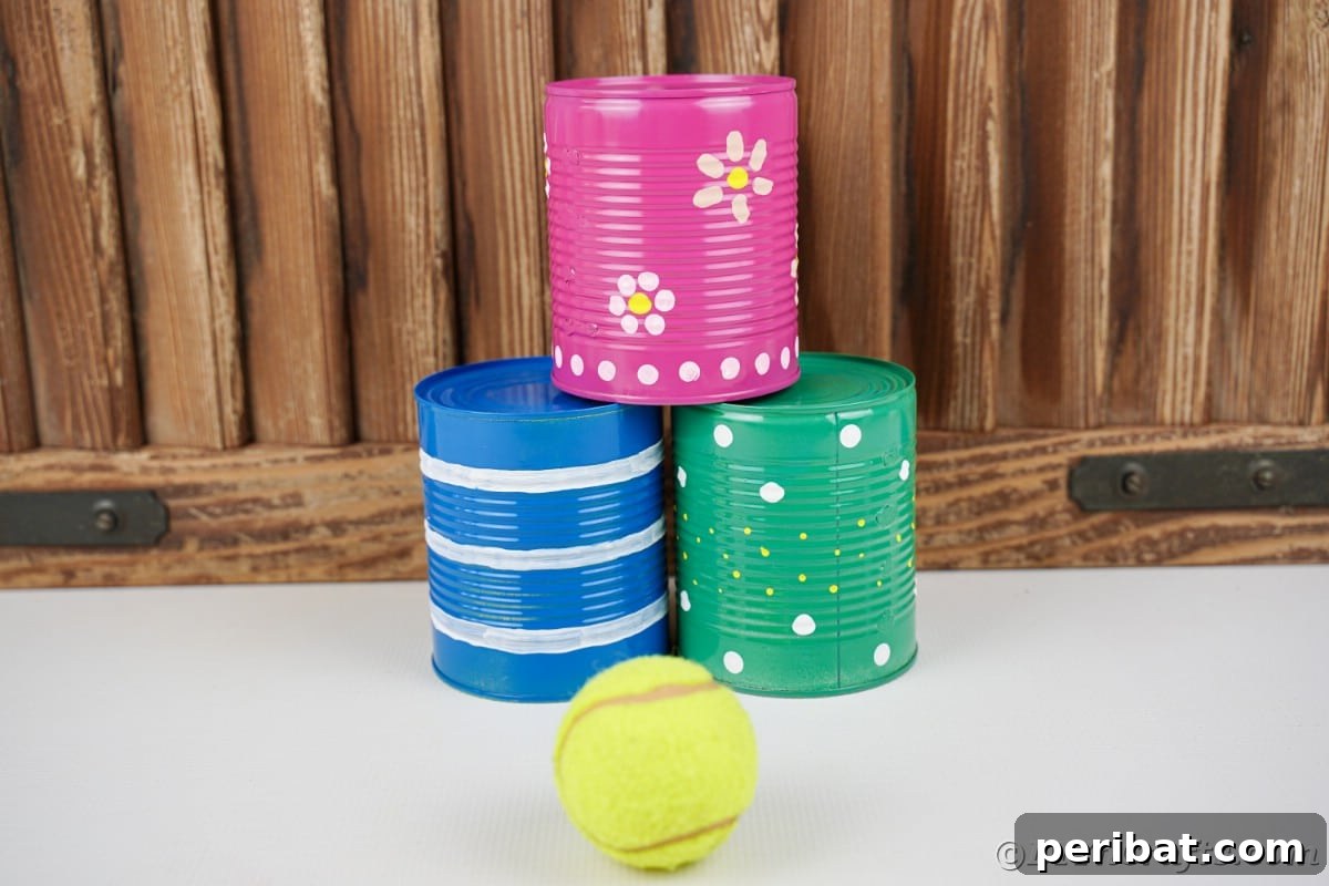 Blue green and pink tin cans with tennis ball in front of wood paneling