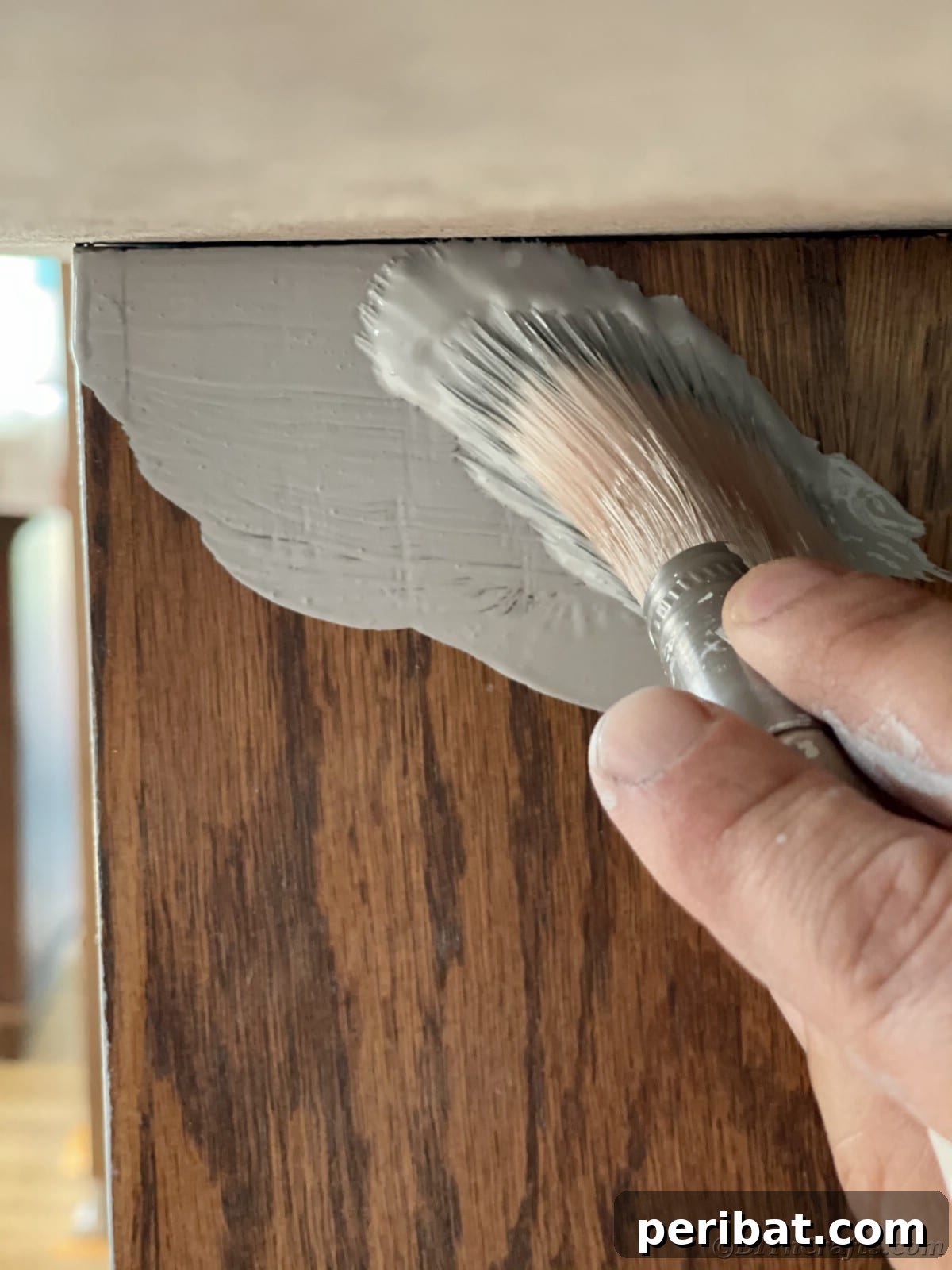 Painting a woodgrain cabinet with primer, preparing it for a fresh new look
