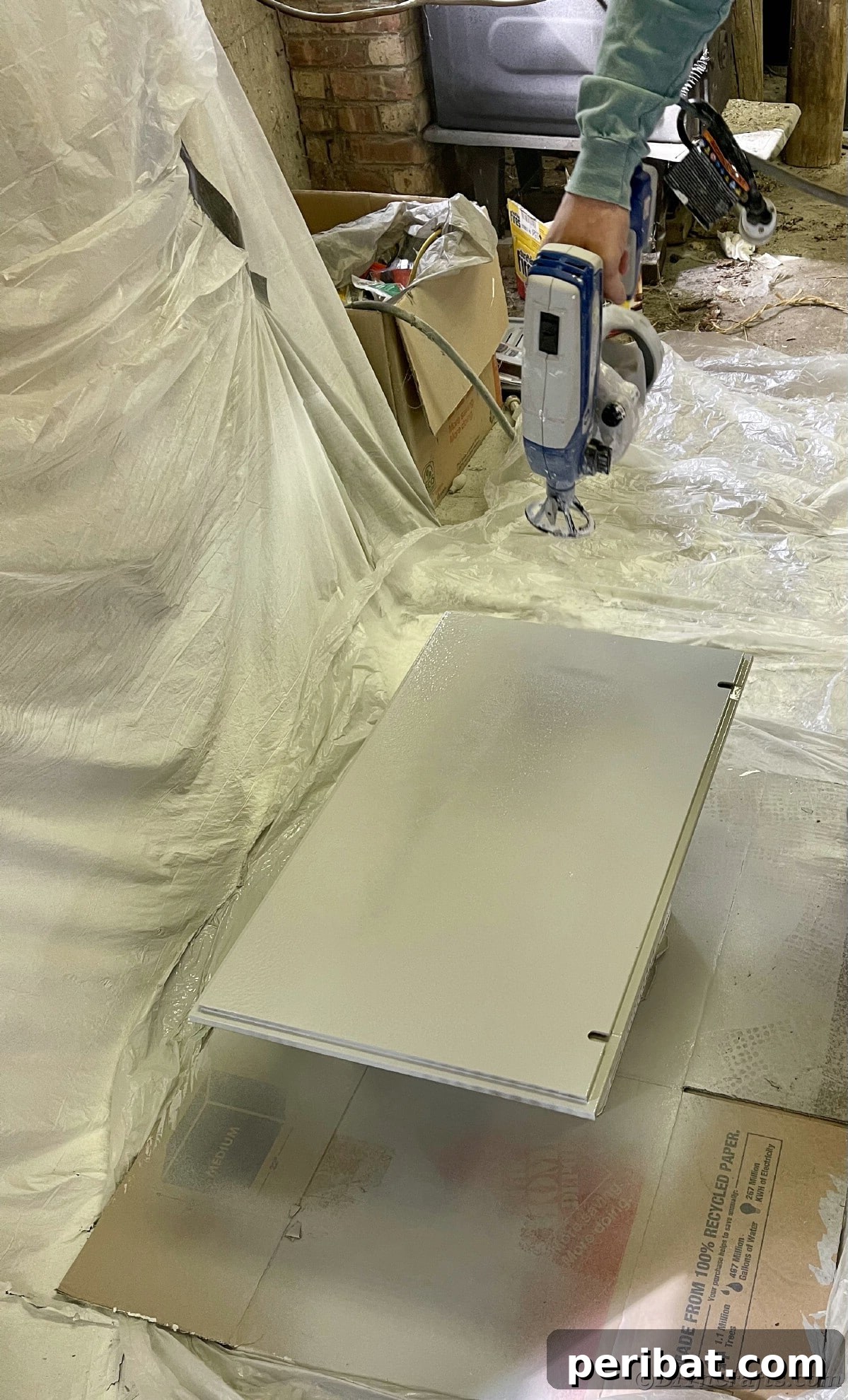 Spray painting a door for a cabinet, ensuring an even and professional finish