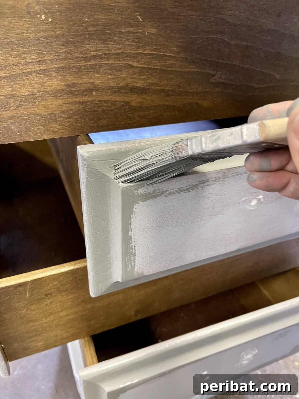 Painting a drawer with gray paint on a brush, applying the first coat with care