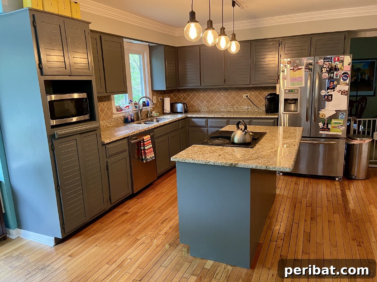 Kitchen interior featuring stylish gray cabinets and a large island, showcasing the completed renovation