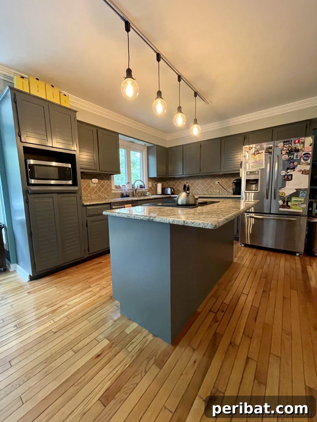 Modern kitchen with gray cabinets, elegant dangling lights over the island, and a clean aesthetic