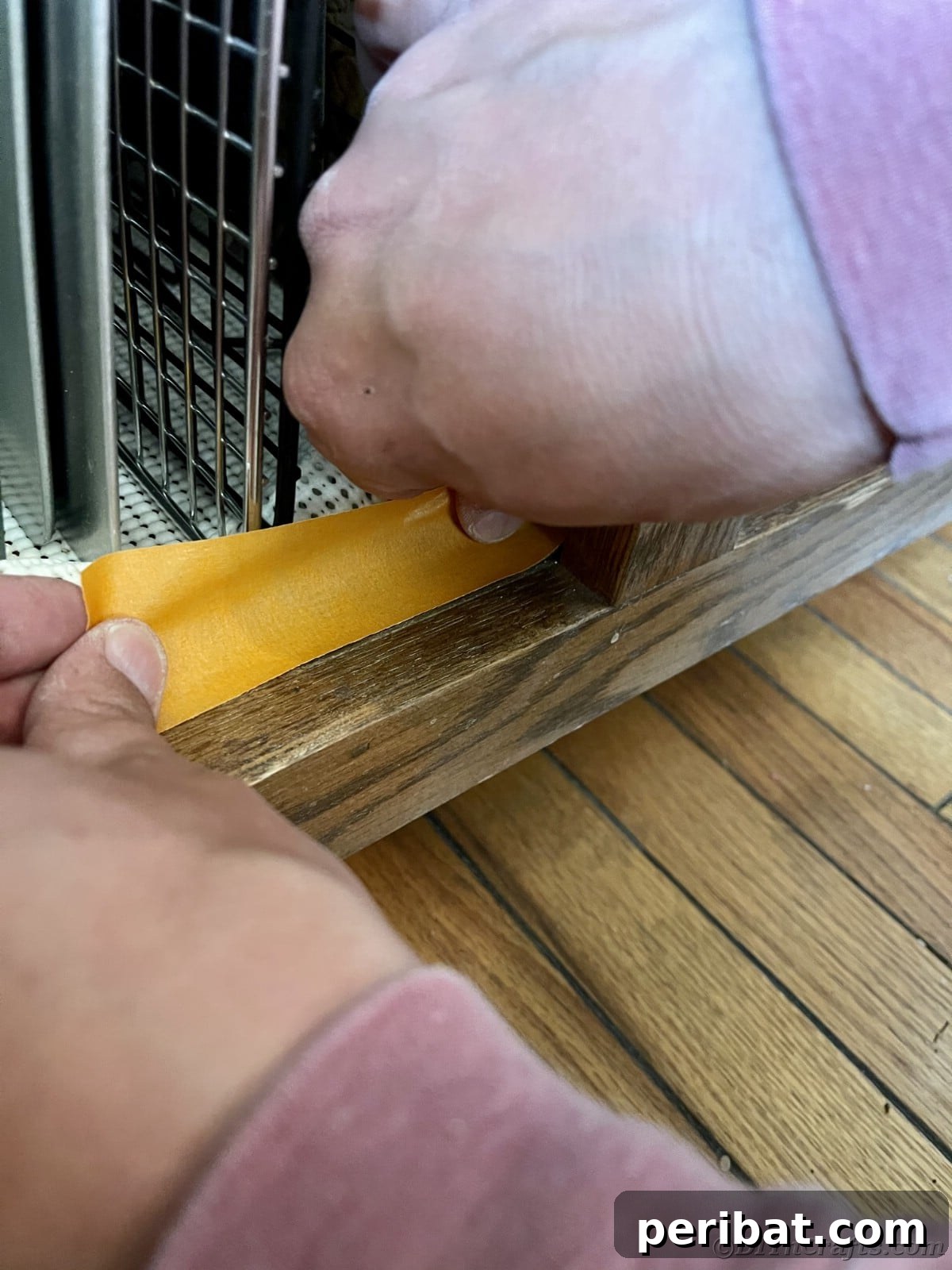 Adding painter's tape meticulously around kitchen appliances, ensuring protection during cabinet painting