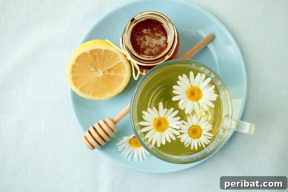 From Garden to Gourmet 10 Edible Flowers to Cultivate 8 A cozy flat lay featuring a bowl of chamomile tea, accompanied by sliced lemon and a dollop of honey, all arranged on a blue plate.