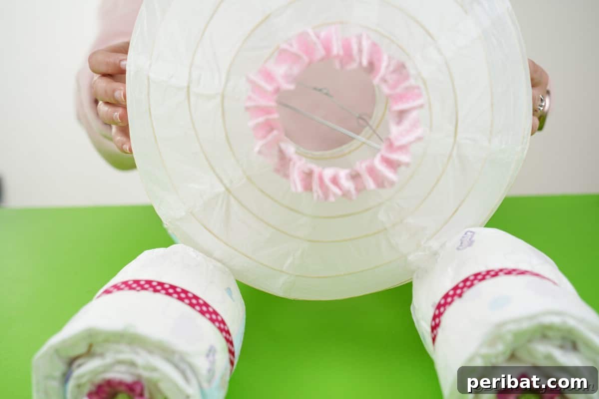 Enchanting Diaper Carriage Baby Shower Surprise 16 Hands placing paper lantern on its side on diaper "wheels"