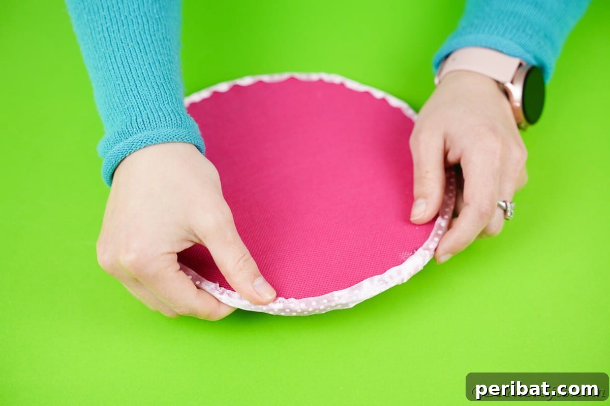 Craft Your Own Darling Pacifier Diaper Cake 9 Handing putting ribbon on top edge of pink circle