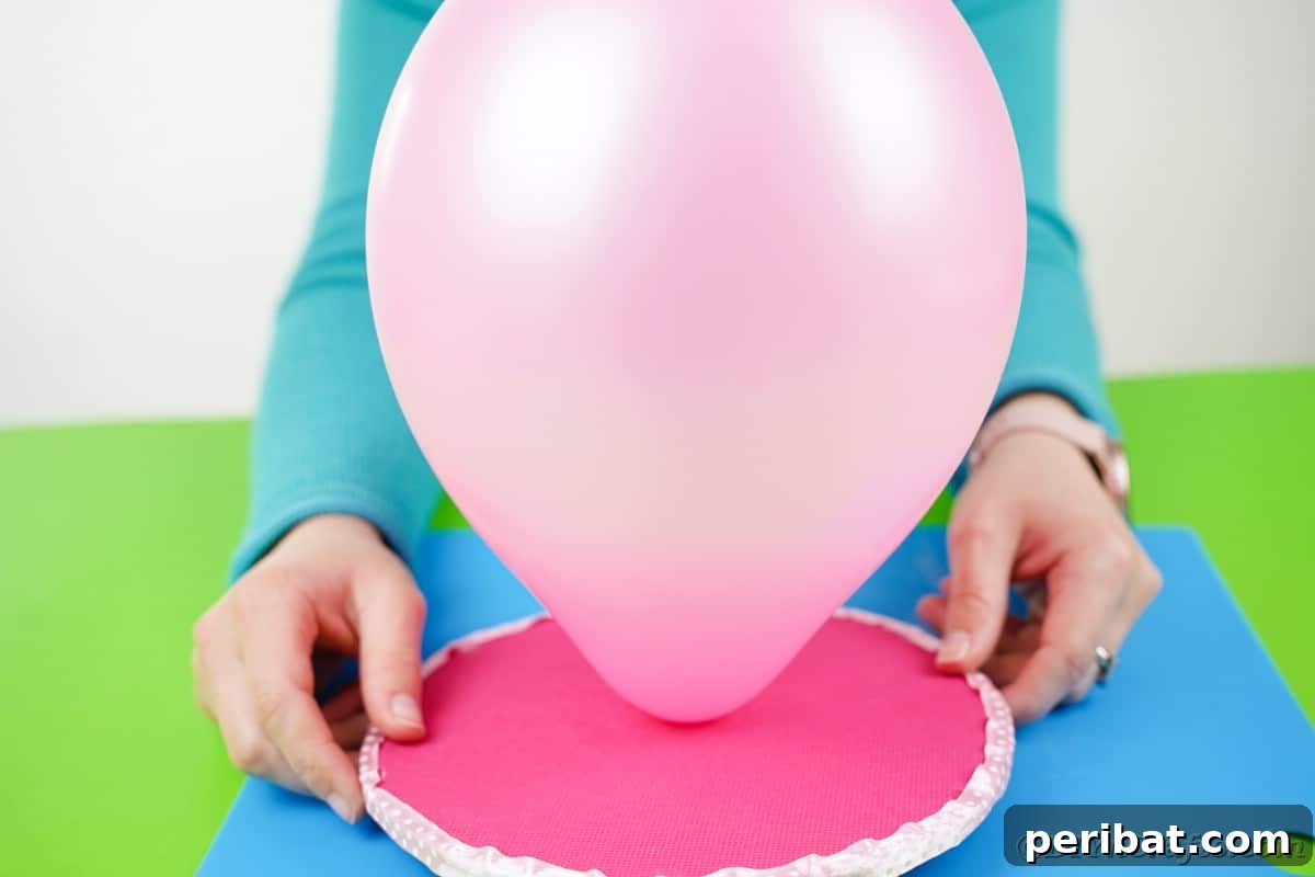 Craft Your Own Darling Pacifier Diaper Cake 11 Pushing balloon through hole in pink cardboard circle