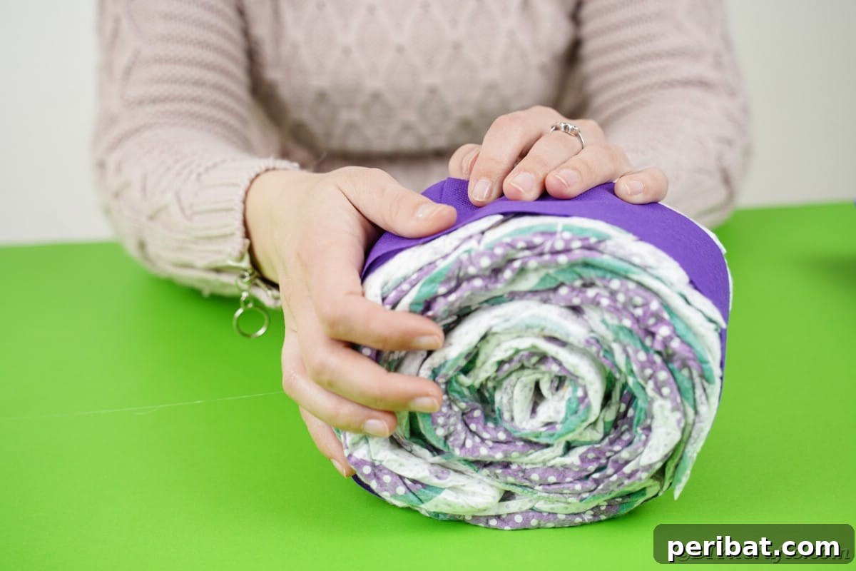 Fluttering Baby Delight: DIY Butterfly Diaper Cake 8 Wrapping a rolled diaper with purple paper, creating a neat and colorful base for the butterfly wing section.