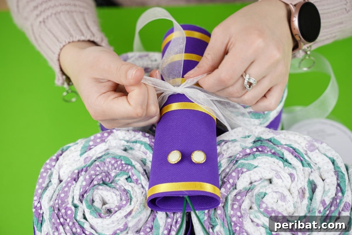 Fluttering Baby Delight: DIY Butterfly Diaper Cake 14 Hands meticulously tying a sheer white ribbon around the middle of the butterfly body, forming a elegant bow.