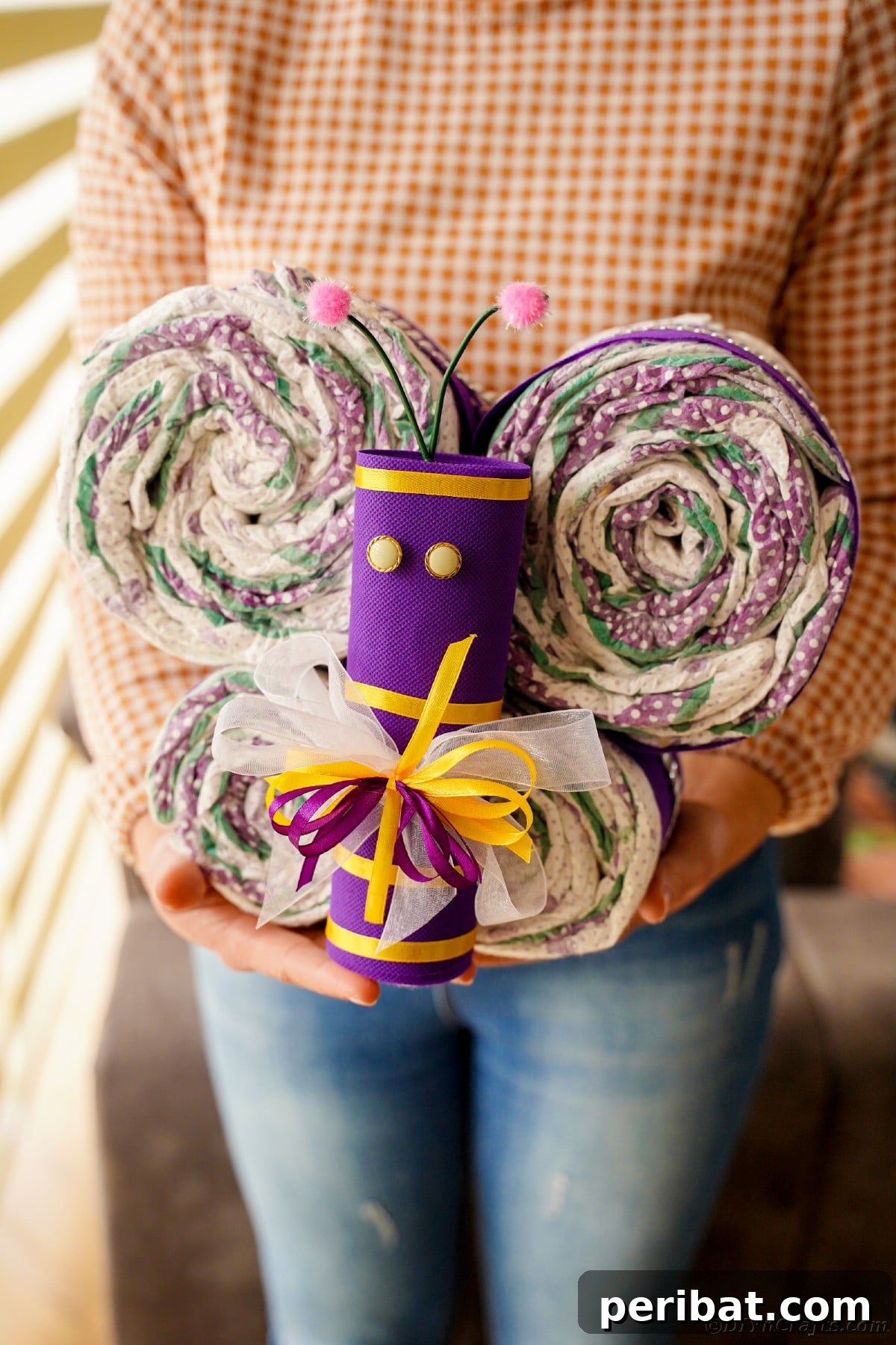 Fluttering Baby Delight: DIY Butterfly Diaper Cake 16 A woman in jeans proudly holding a beautifully crafted butterfly diaper cake, showcasing it as a heartwarming baby gift.